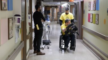 Pushing patient in wheelchair with Project Sunshine. Behind the scenes film shoot for 5-part promotional campaign to highlight the scope and impact of their work. Pediatric patients. Non profit. Production services.