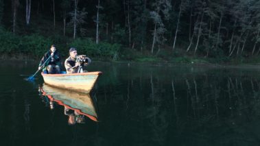 Director Jordan Ehrlich on boat with crew member in lake. Non profit video production with Asian Aid. Outdoor filming. Promotional content. Crew in field. Nature shoot.